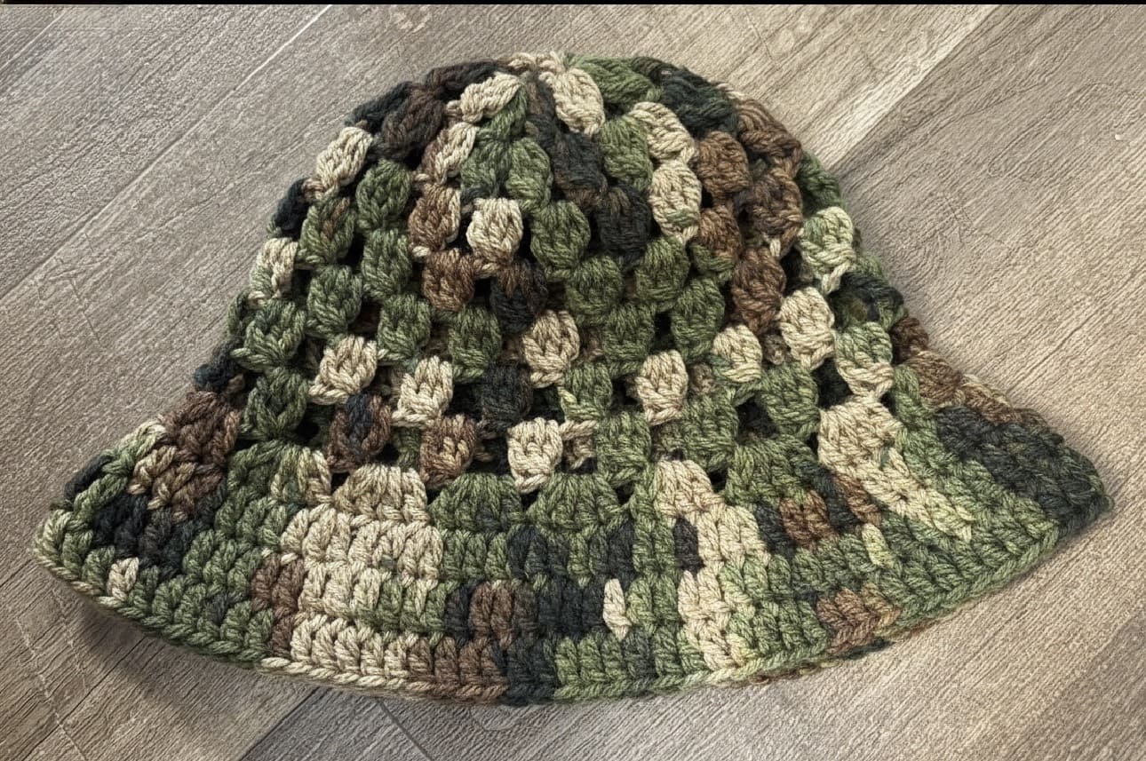 Camouflage-patterned crochet hat on a wooden surface